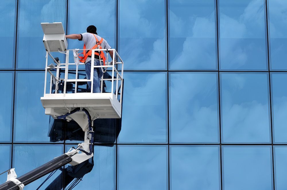 A Man Is Cleaning The Windows Of A Building — Crystal Clear In Armidale, NSW