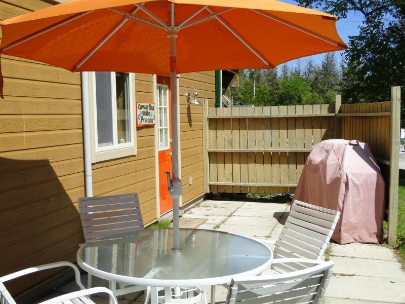 A table and chairs under an orange umbrella in front of a house