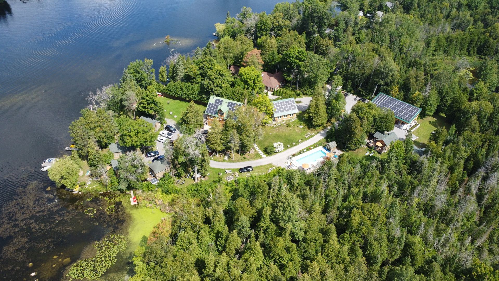 An aerial view of a house on a small island in the middle of a lake surrounded by trees.