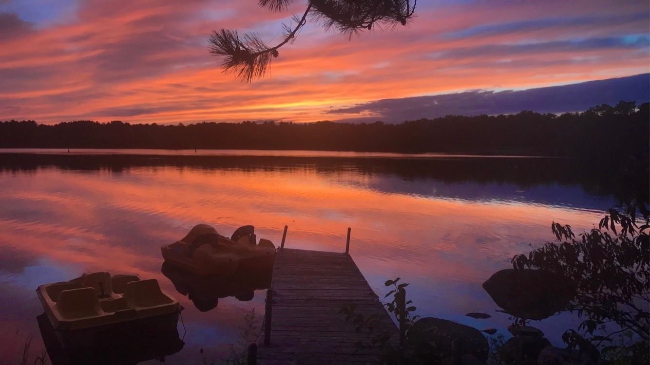 A sunset over a lake with a dock in the foreground.