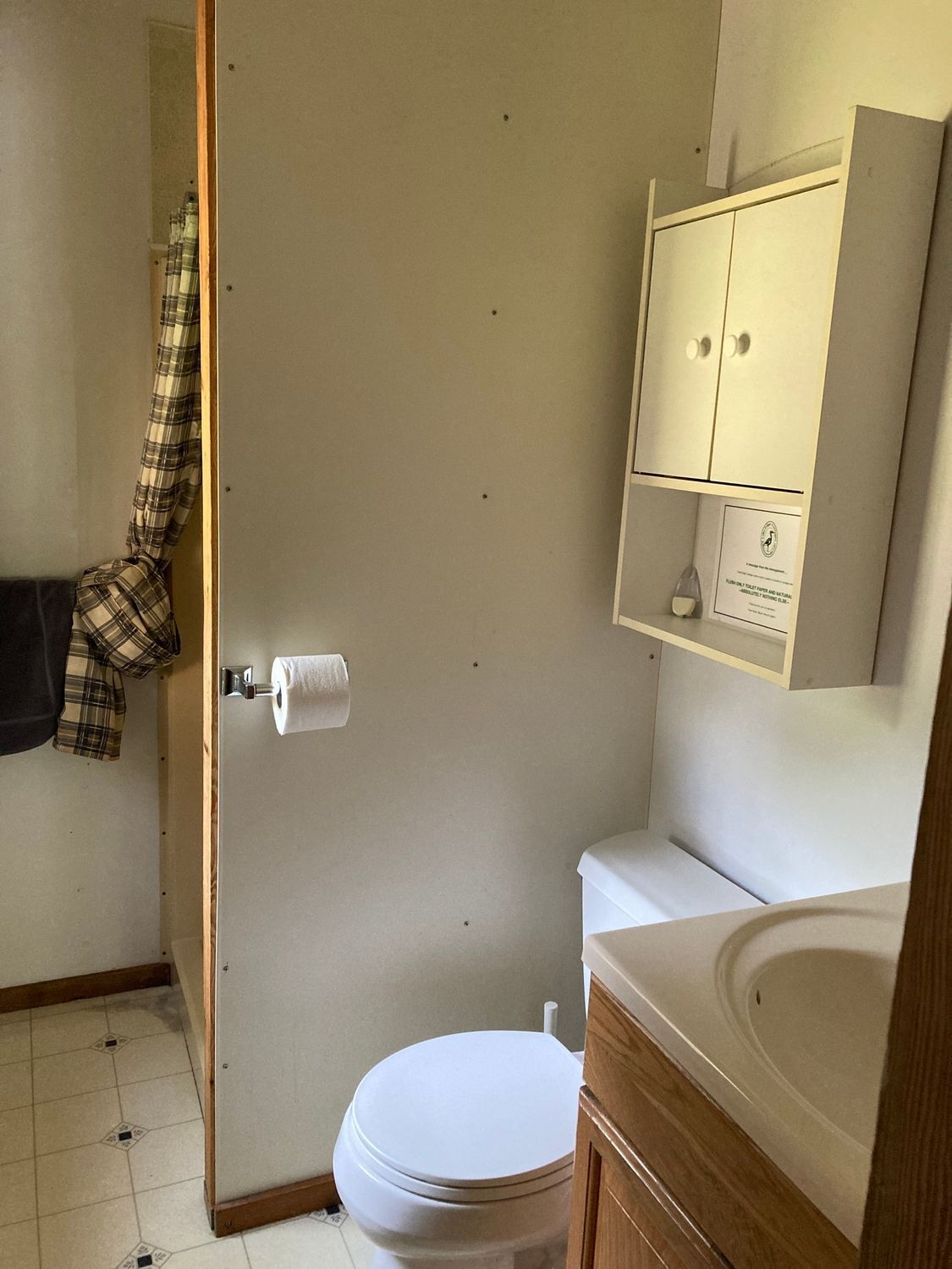 A bathroom with a toilet , sink and cabinet.