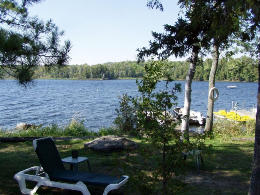A chair sits in the grass near a lake