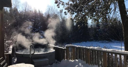 A hot tub is sitting on a deck in the snow.