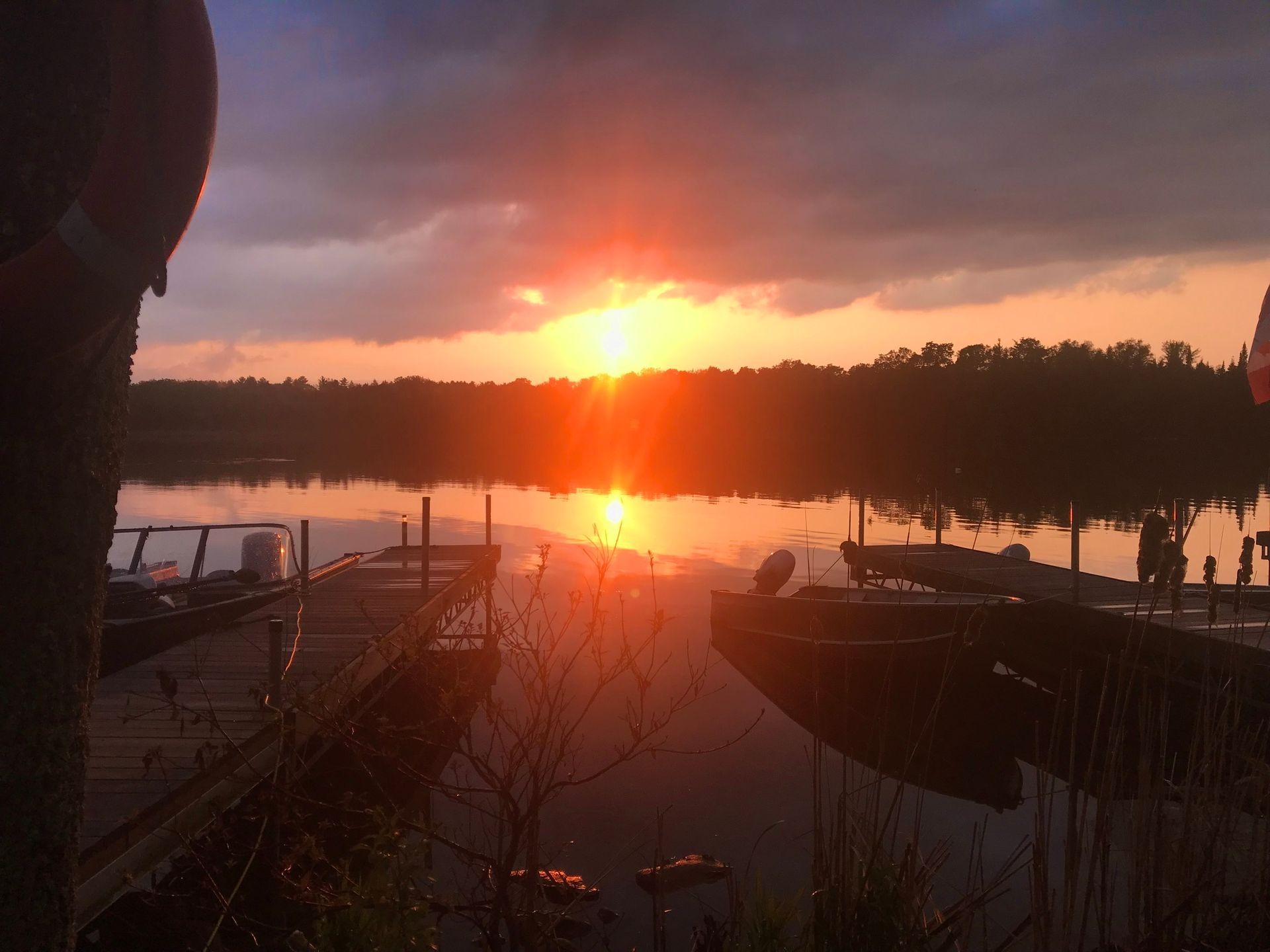 A sunset over a lake with boats docked at a dock.