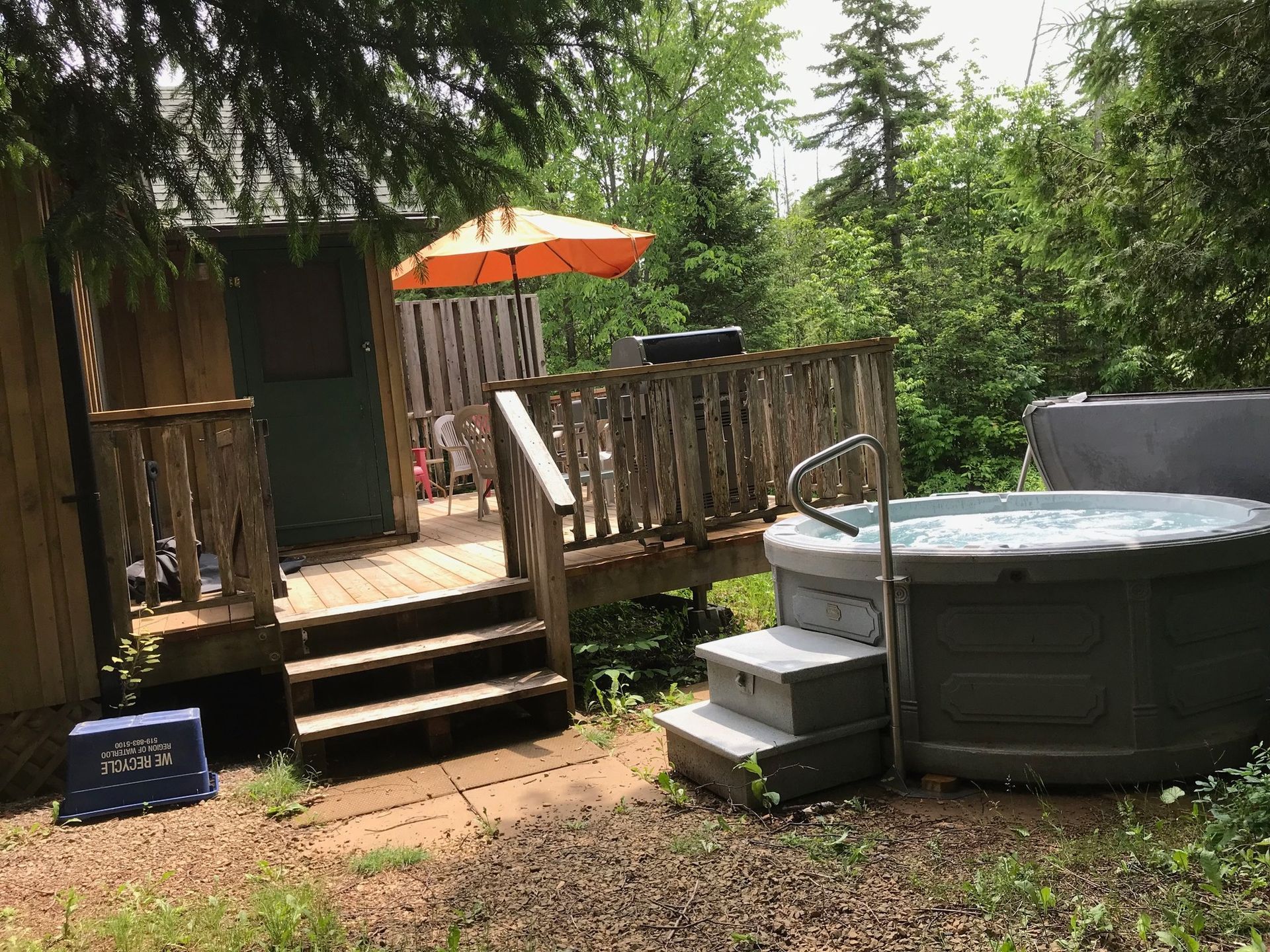 A hot tub is sitting in front of a wooden deck.