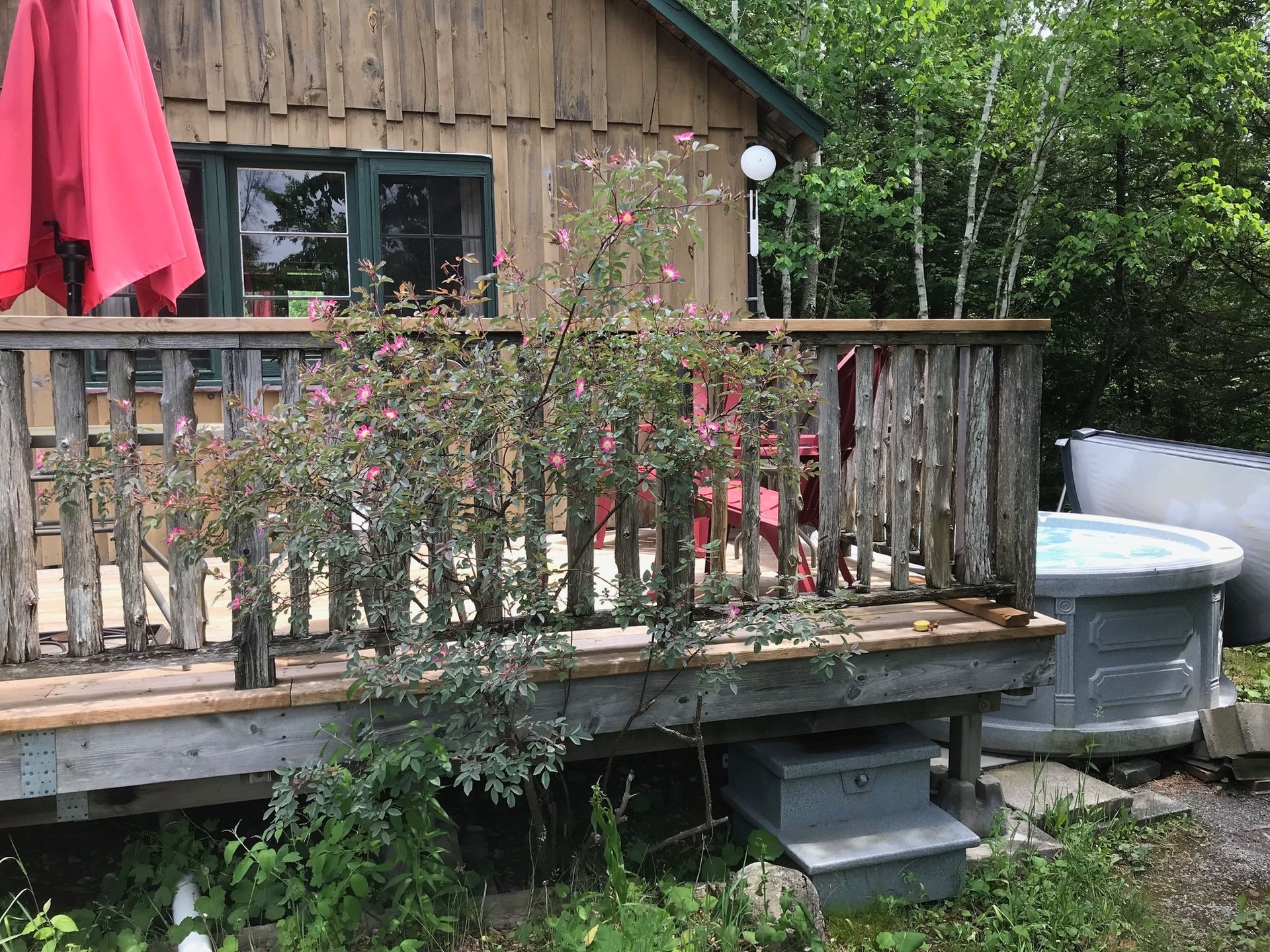 There is a hot tub on the deck of a cabin.