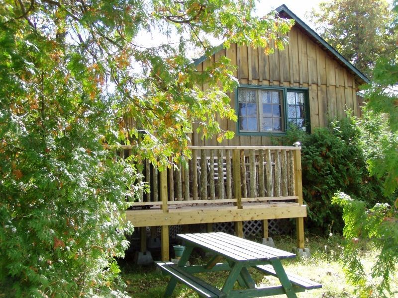 A wooden cabin with a picnic table in front of it