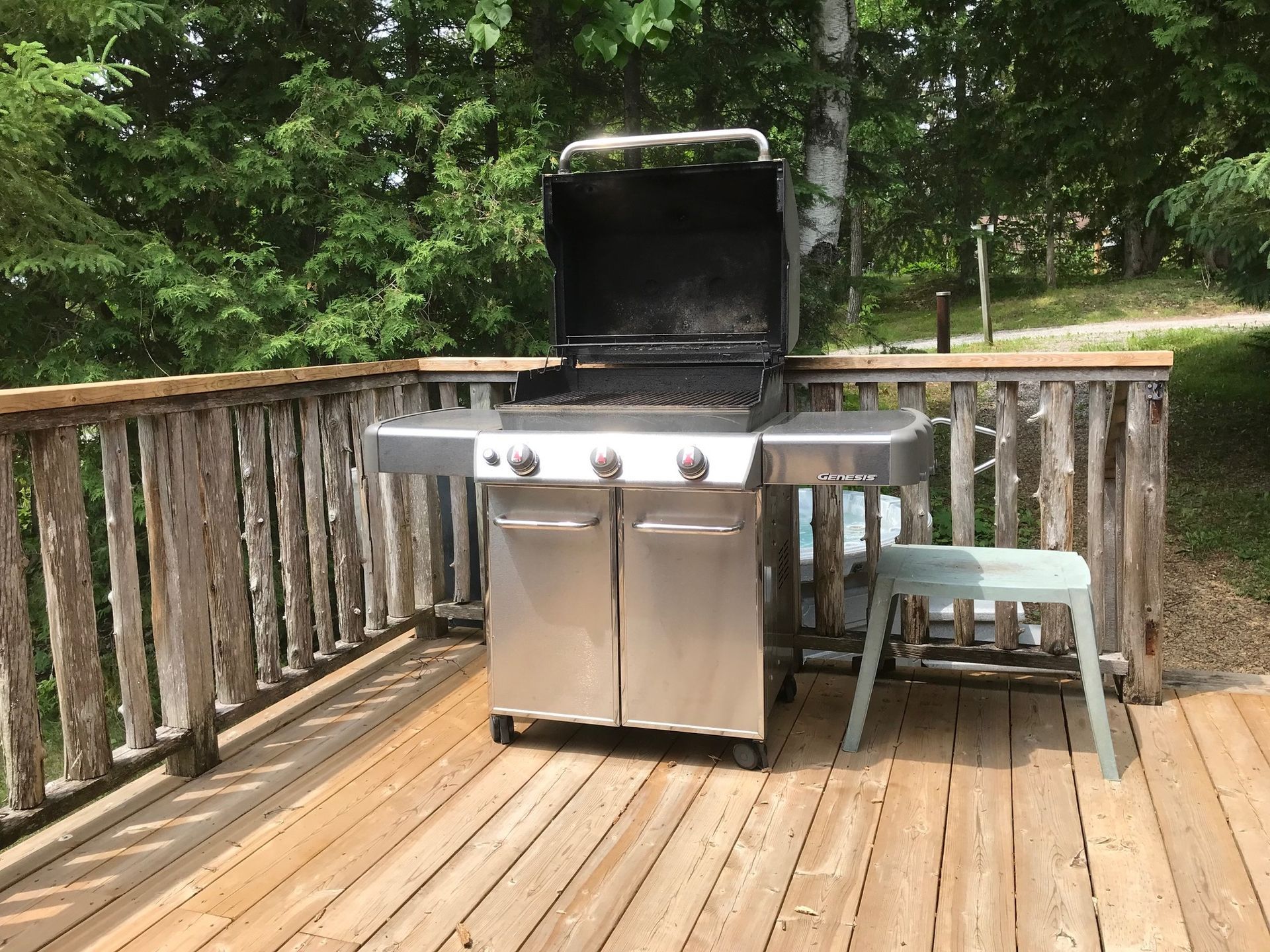A stainless steel grill is sitting on a wooden deck.
