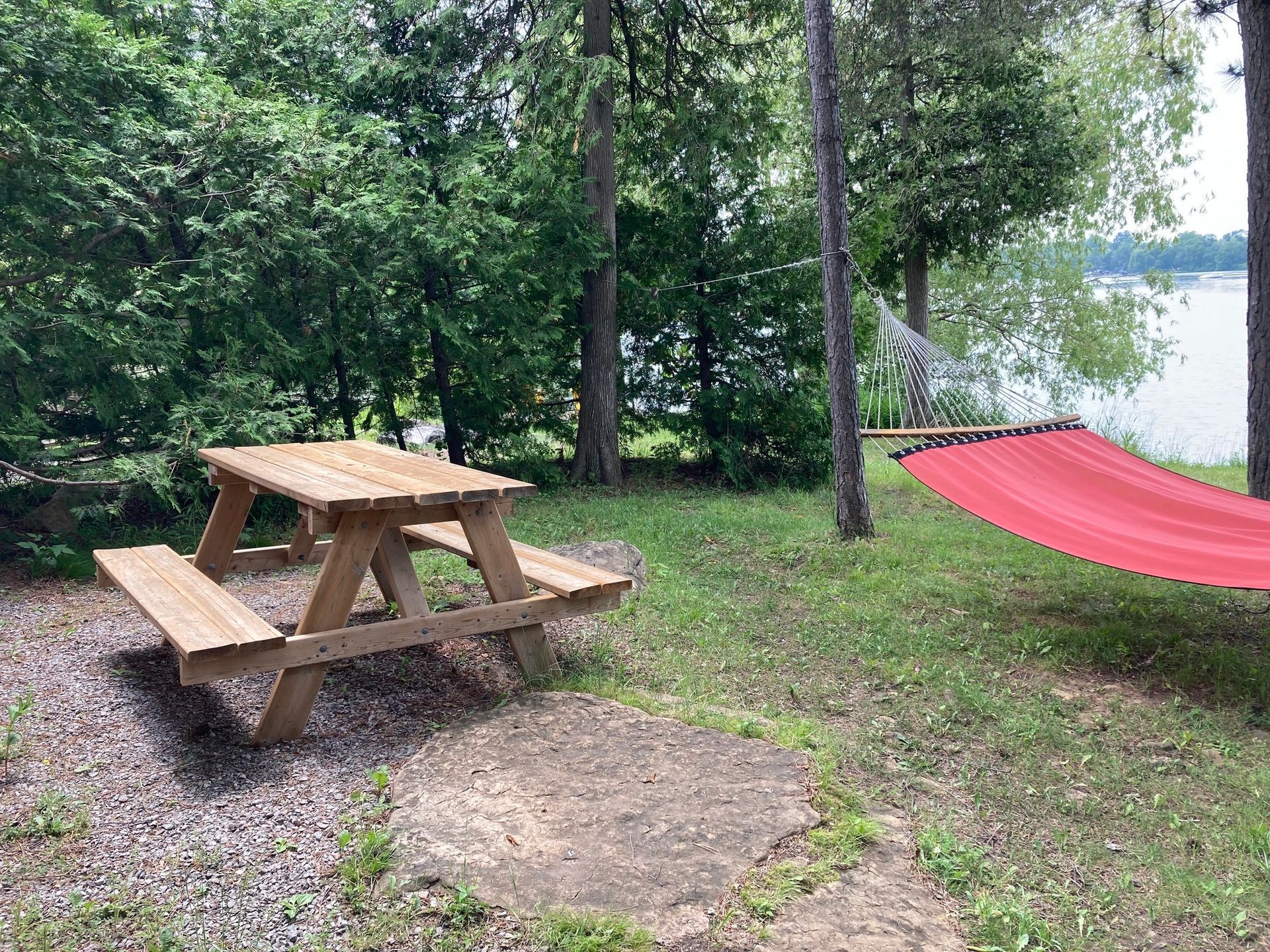 There is a picnic table and a hammock in the grass.