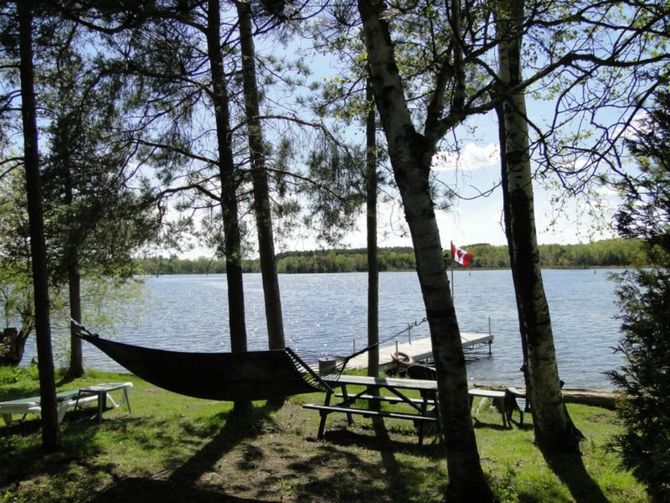 a hammock is hanging over a picnic table near a lake