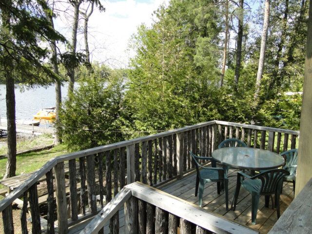 A wooden deck with a table and chairs overlooking a lake