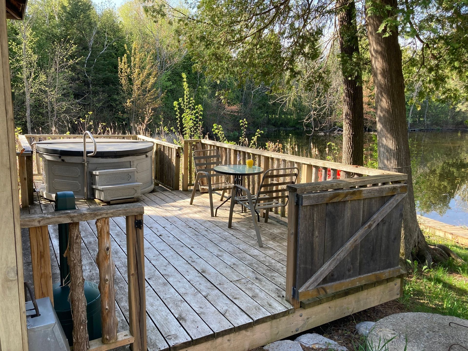 A wooden deck with a hot tub and a table and chairs.