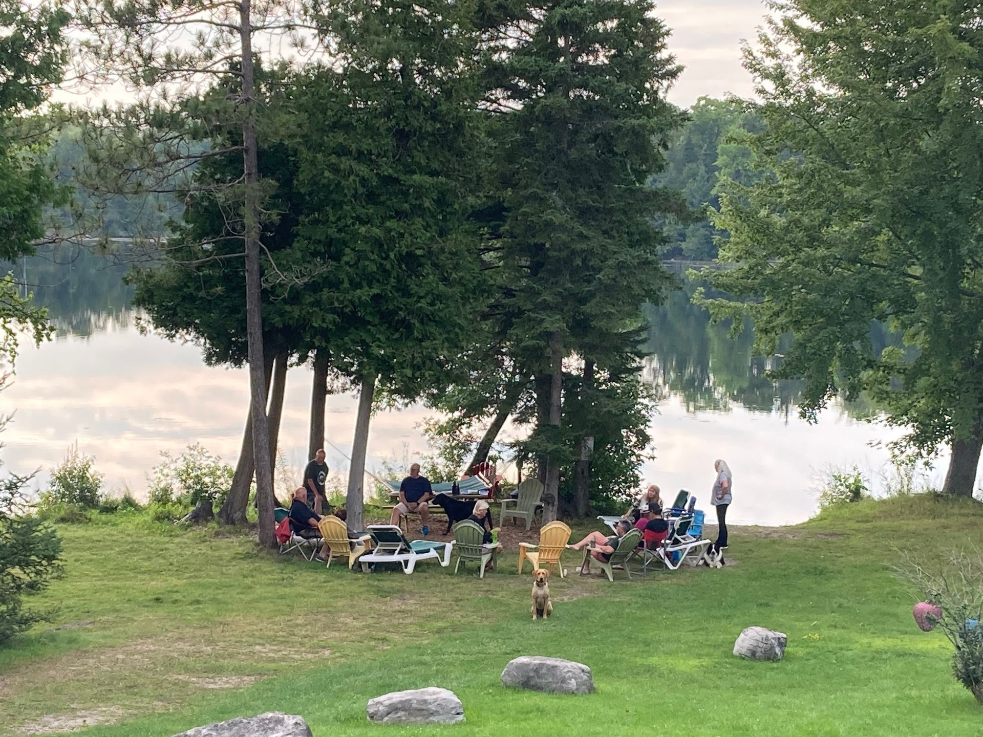 A group of people are sitting around a fire pit near a lake.