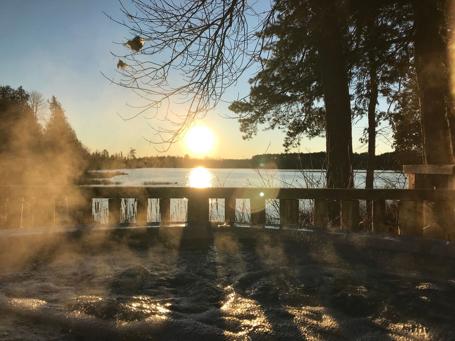 A sunset over a lake with trees in the background