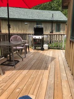 A wooden deck with a table and chairs and a grill.