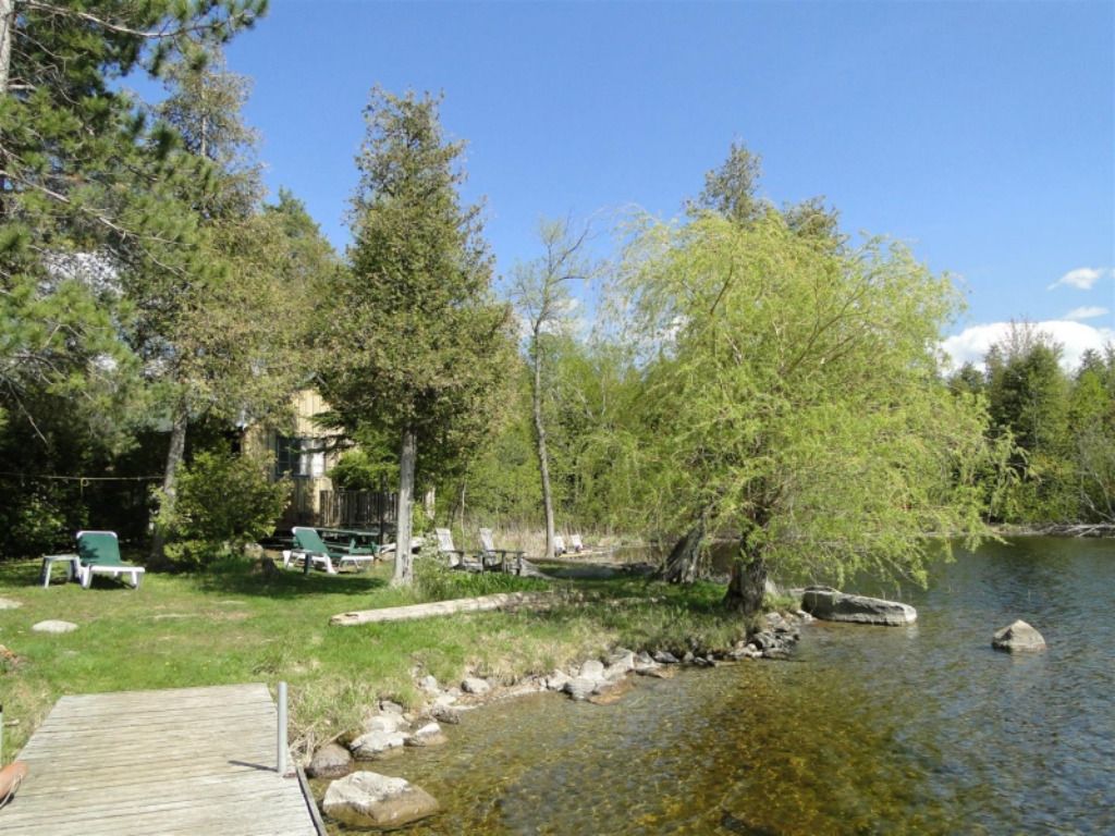 A house is sitting on a small island in the middle of a lake surrounded by trees.