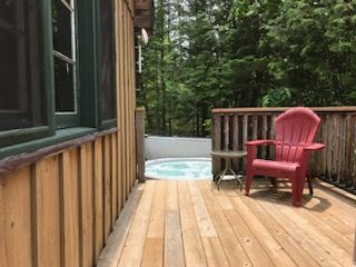A red chair is sitting on a wooden deck next to a hot tub.