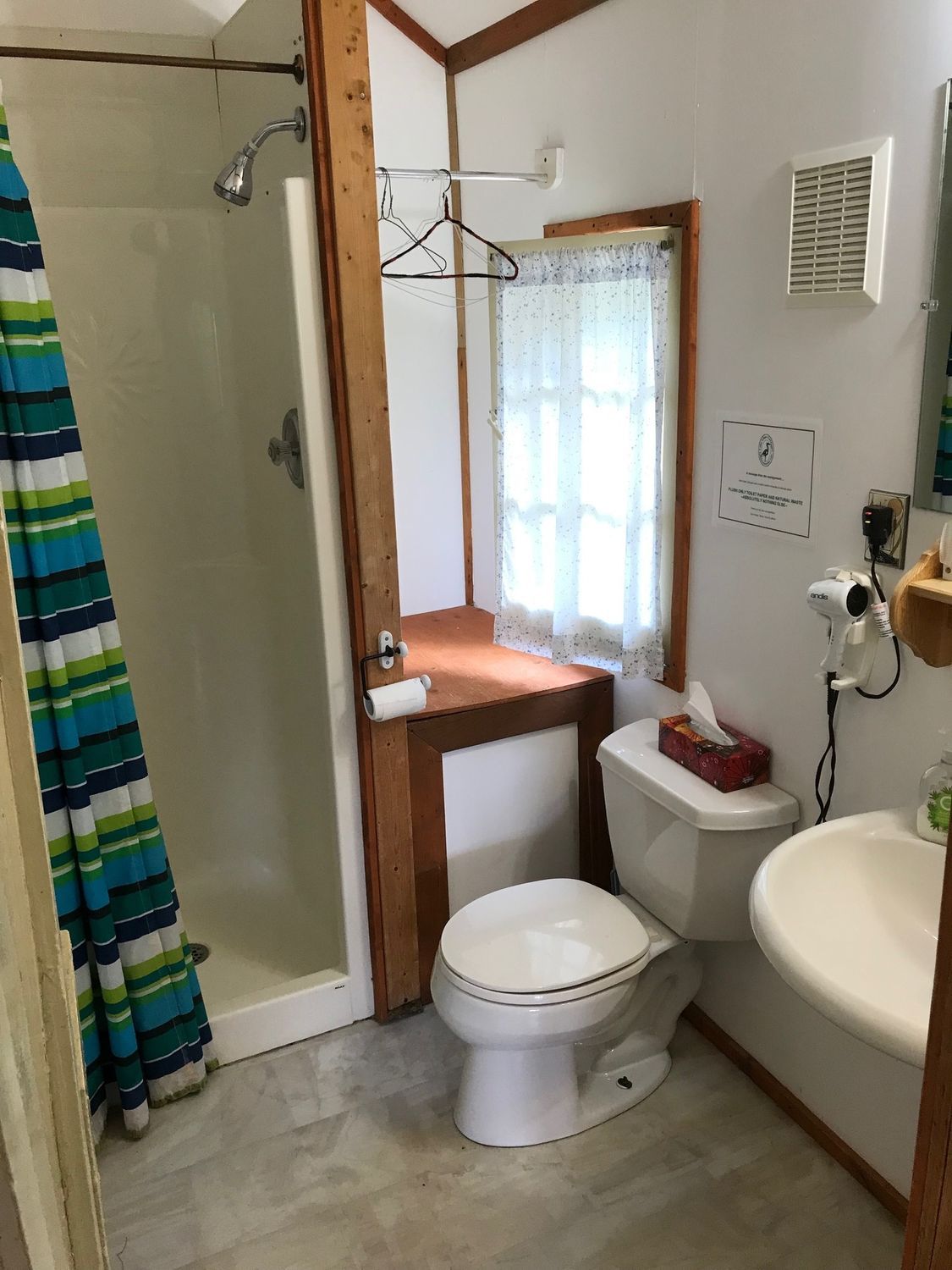 A bathroom with a toilet , sink and shower.