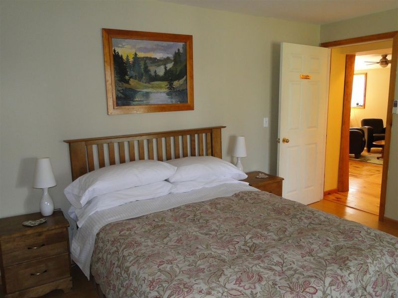 A bedroom with a painting on the wall above the bed