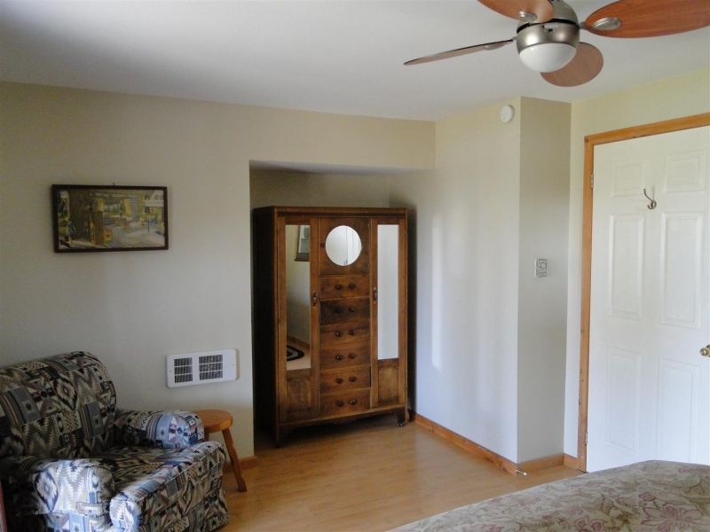 A bedroom with a ceiling fan and a chair