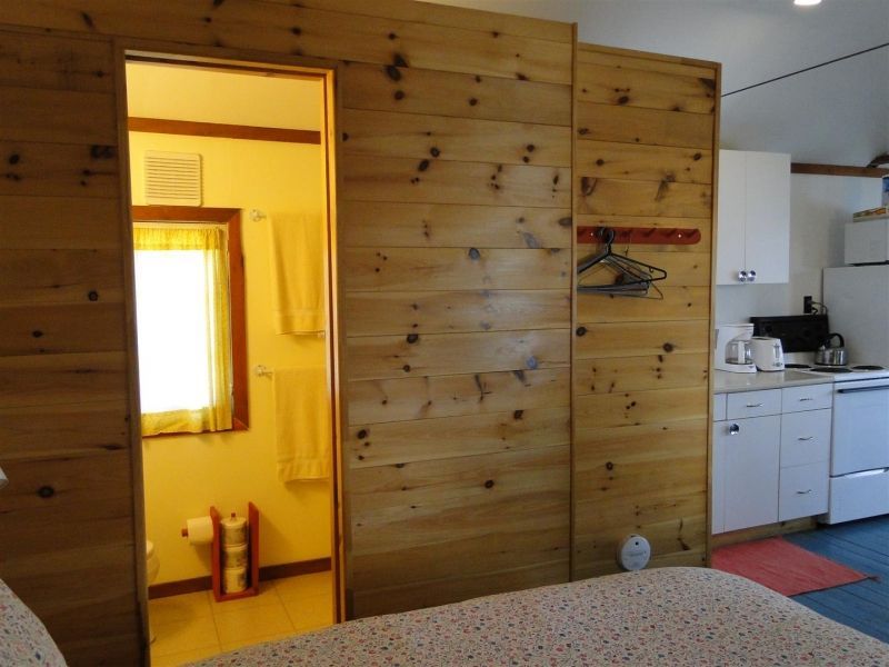 A bedroom with a wooden wall leading to a bathroom