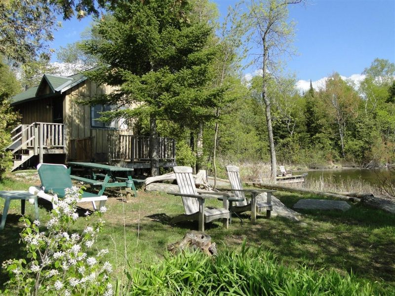 A group of chairs are sitting in front of a cabin.