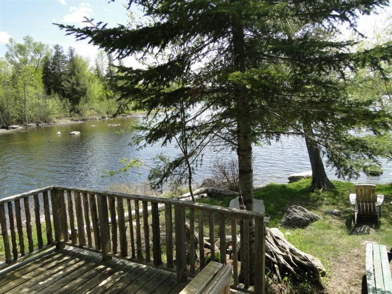 A wooden deck overlooking a lake with trees in the background