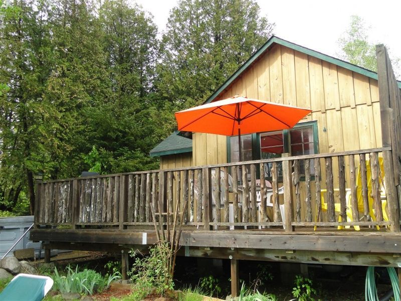 An orange umbrella sits on the deck of a house