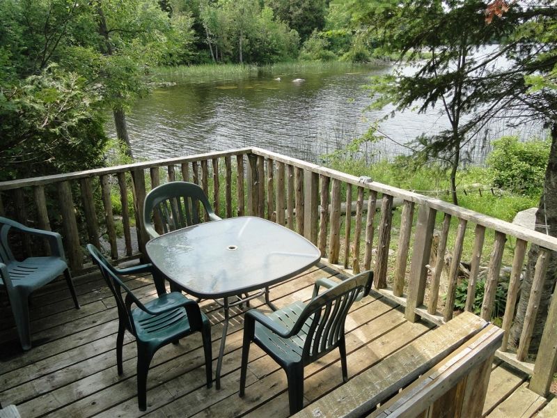 A deck with a table and chairs overlooking a lake