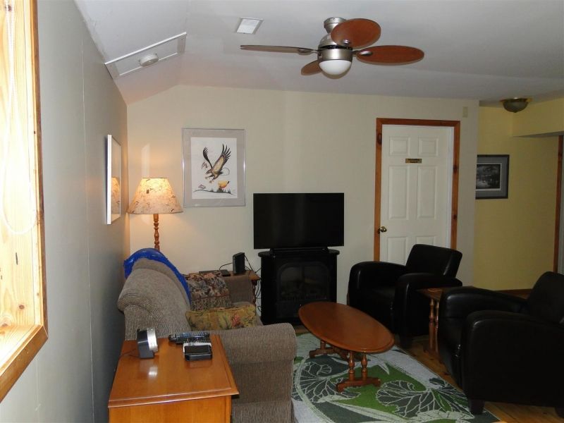 A living room with a ceiling fan and a flat screen tv