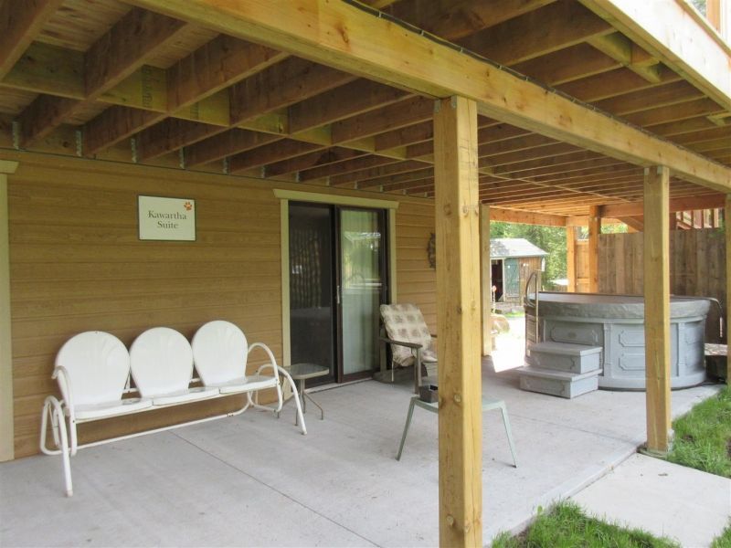 A porch with a bench and chairs and a hot tub
