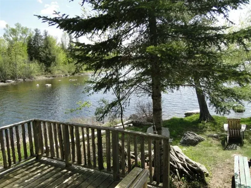 A wooden deck overlooking a lake with trees in the background