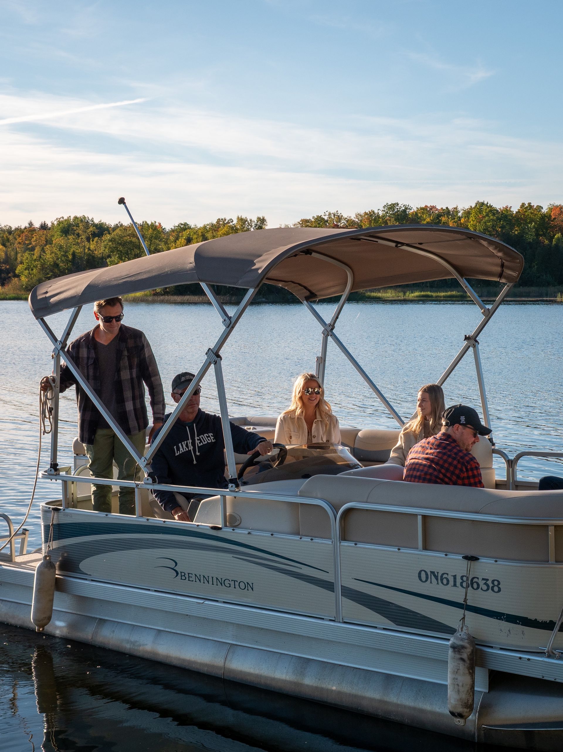 People on a pontoon boat on a lake with a canopy. Sunny day.