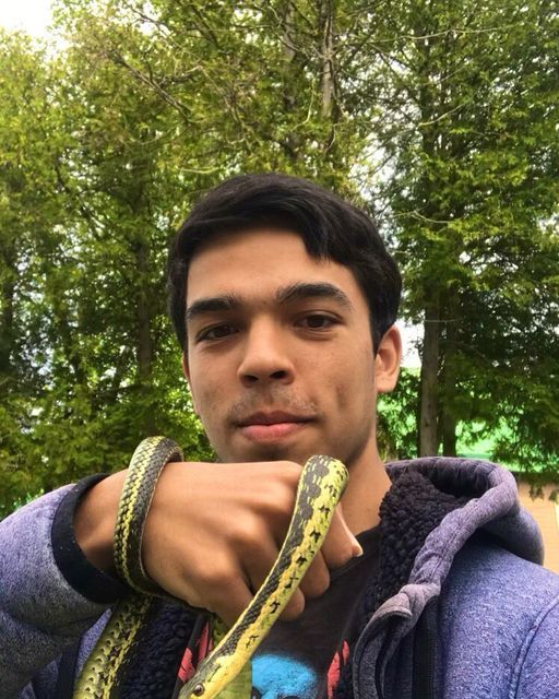 A young man is holding a snake in his hand