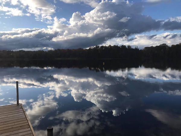 A dock overlooking a lake with clouds reflected in the water