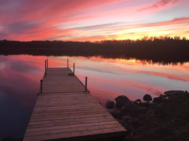 A sunset over a lake with a dock in the foreground