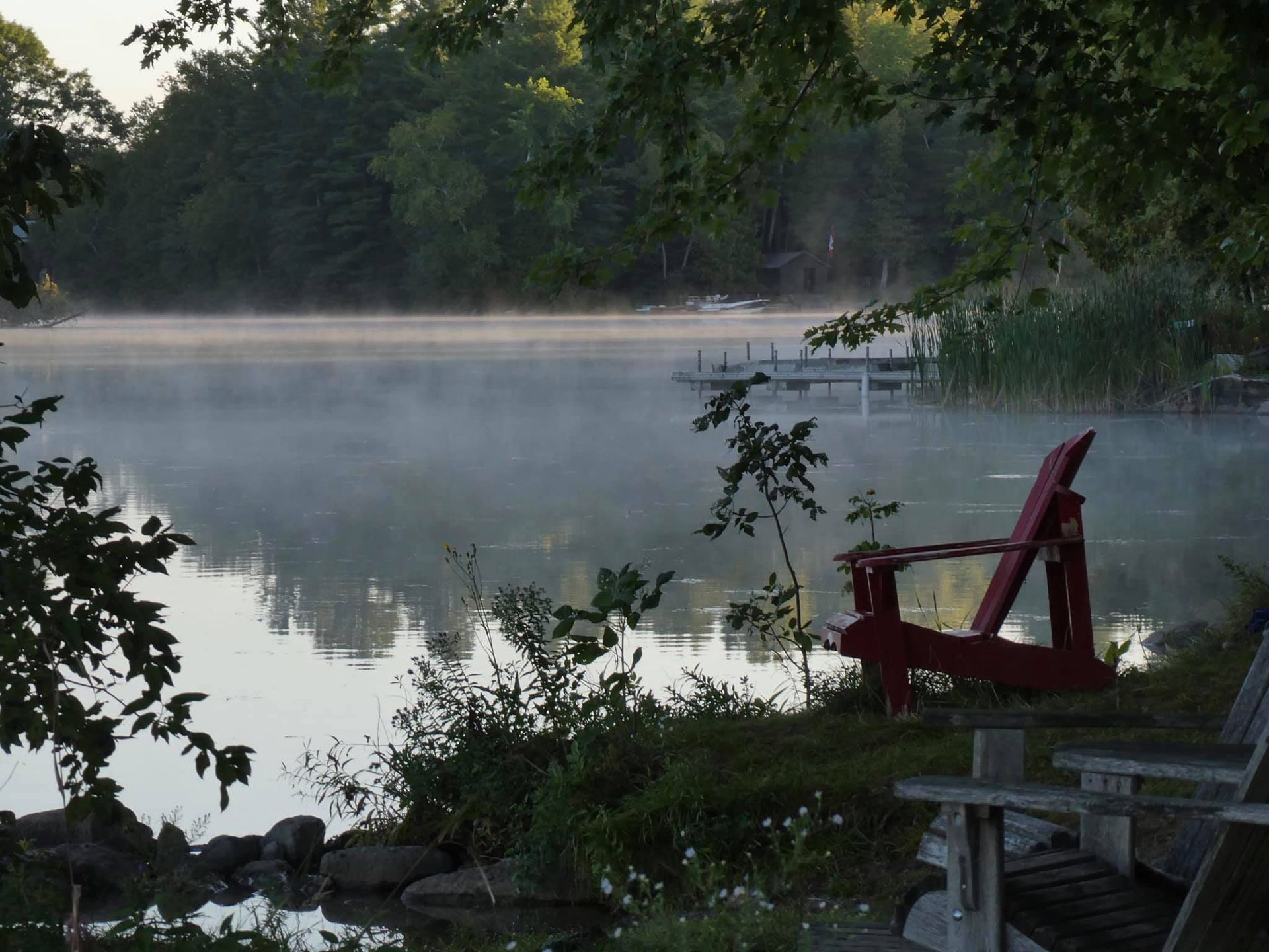A foggy lake with a red chair in the foreground
