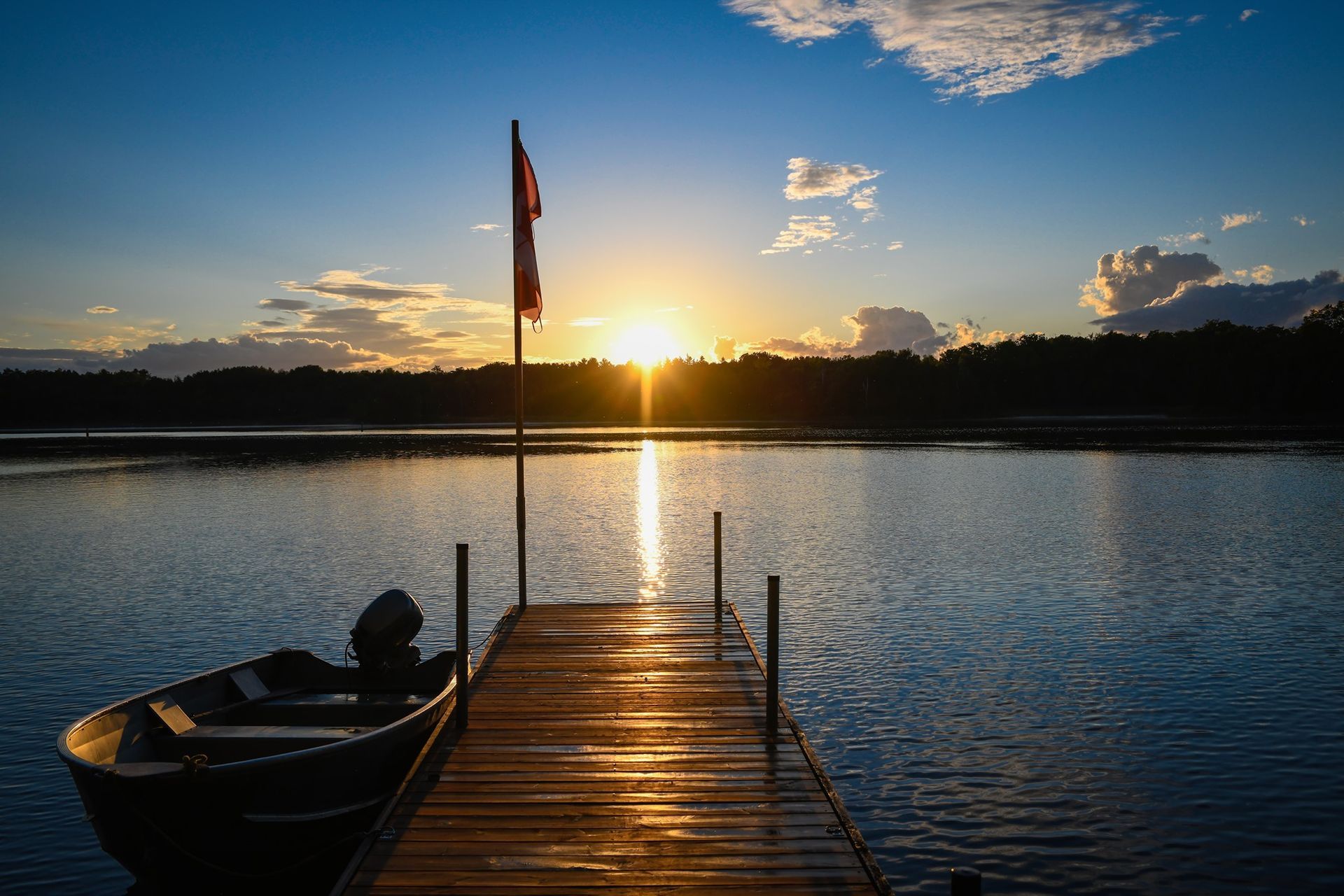 A boat is docked at a dock on a lake at sunset.