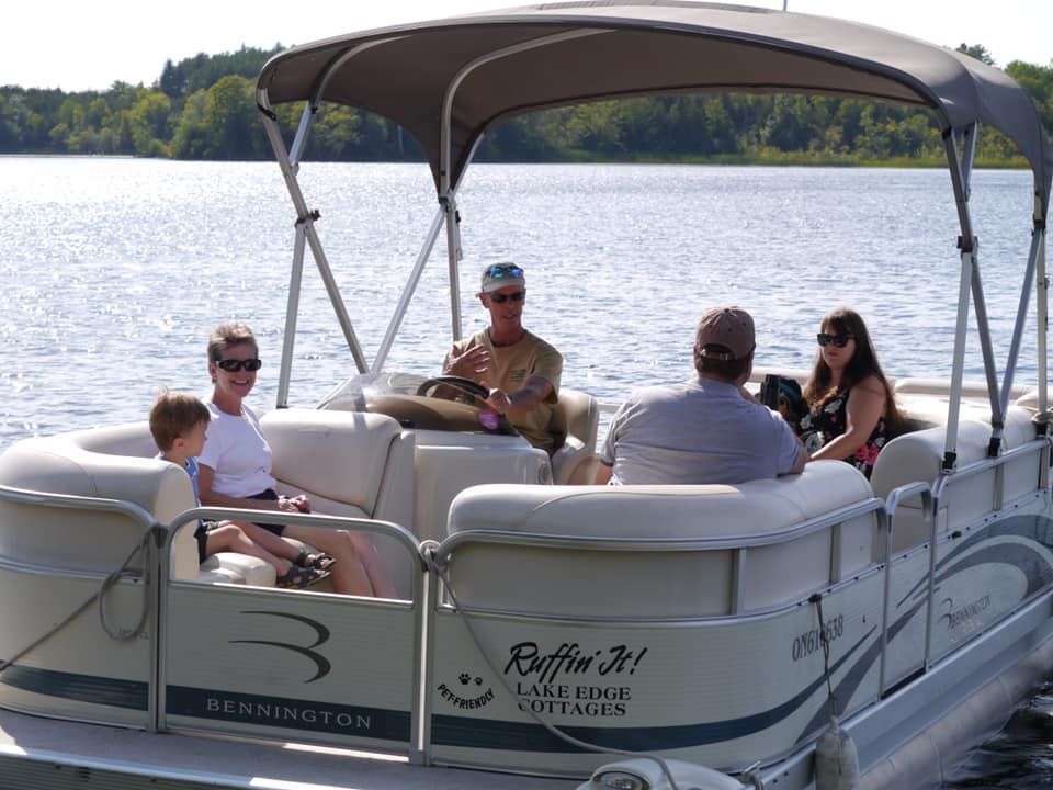 A group of people are sitting on a pontoon boat on a lake.