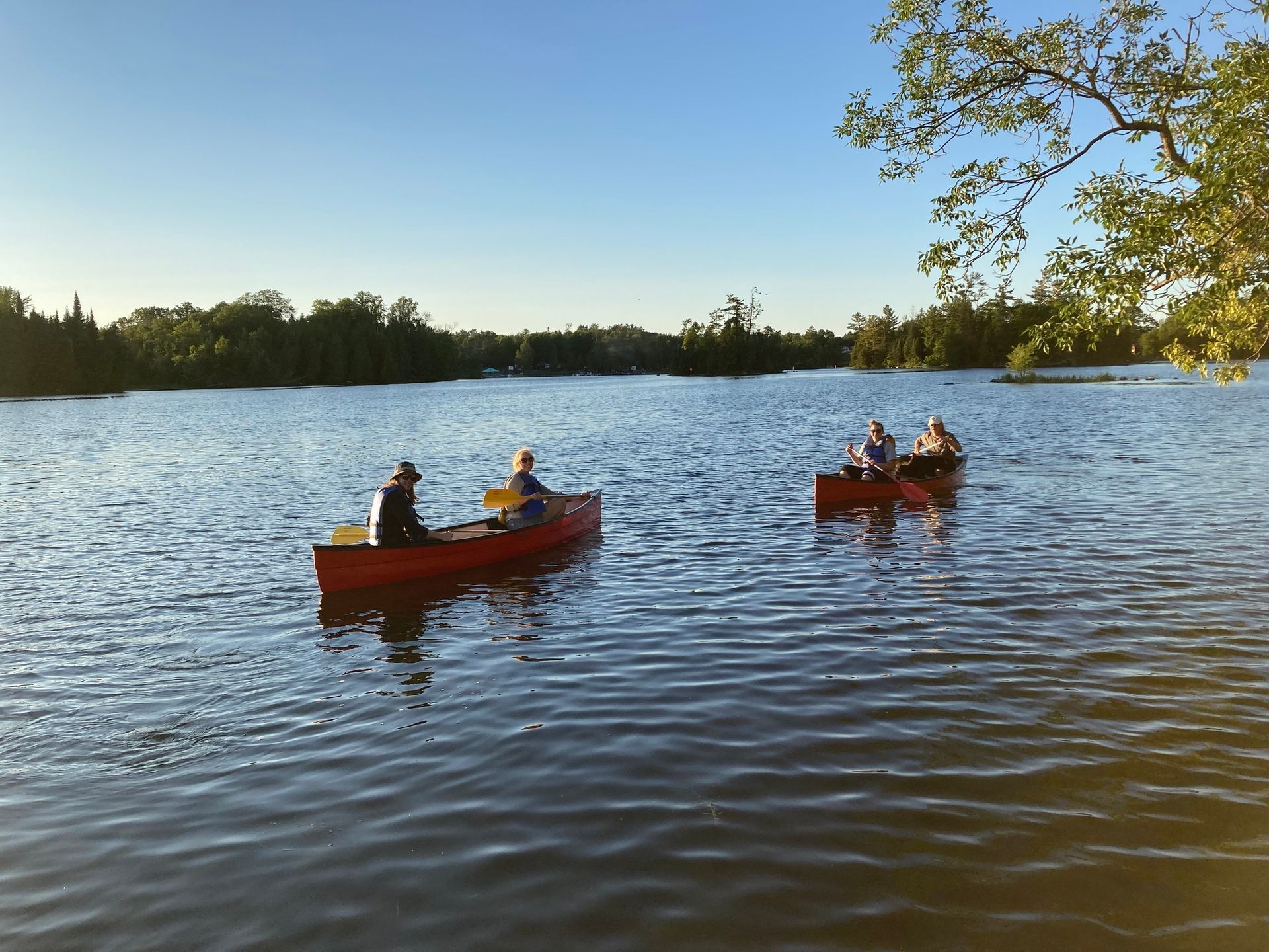 Three people in red canoes on a lake