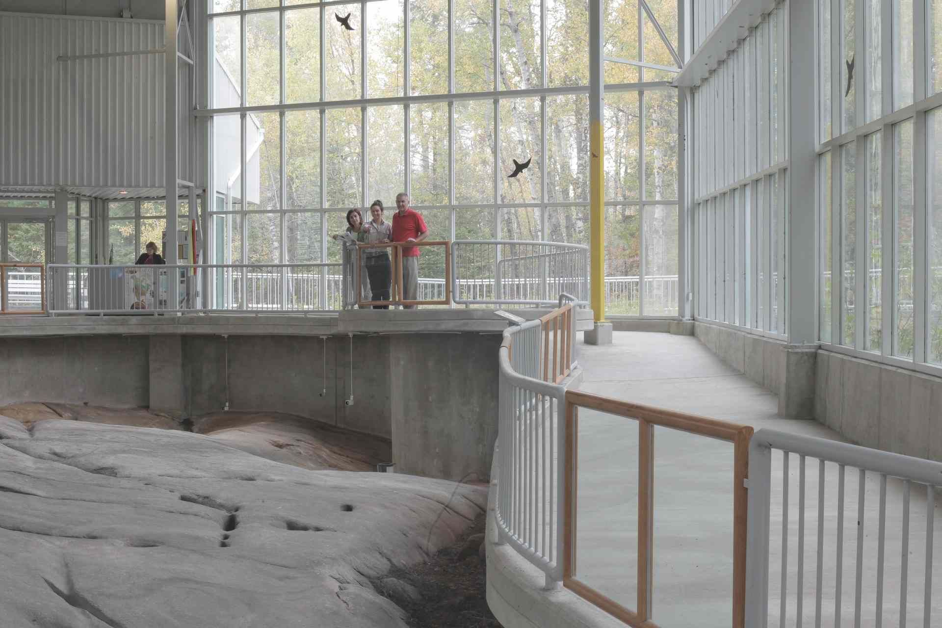 A group of people are standing in front of a large window in a building.