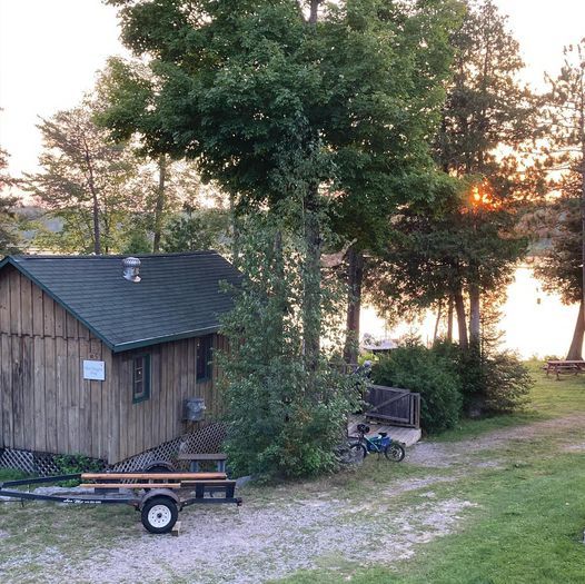 A small wooden house with a picnic table on a trailer in front of it.