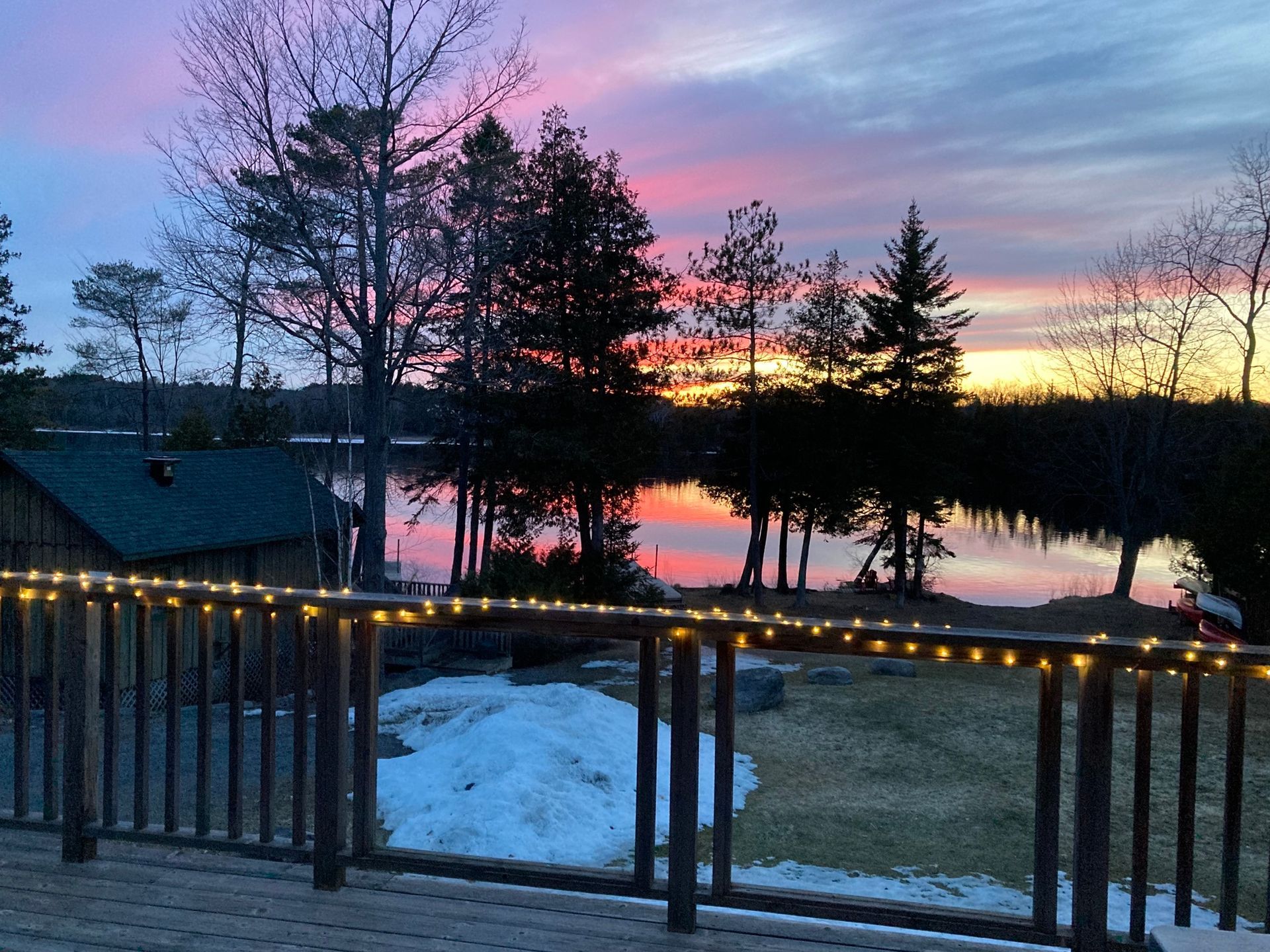 A deck overlooking a lake with a sunset in the background