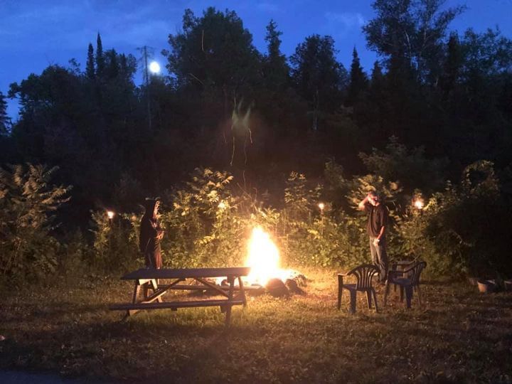 A group of people are sitting around a campfire at night.