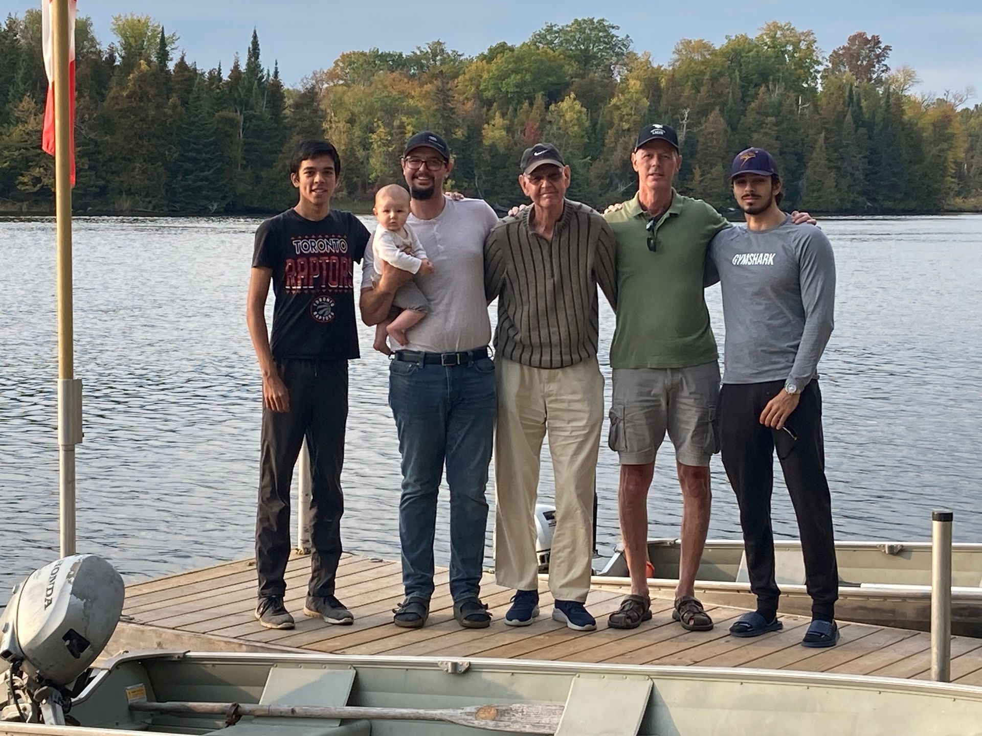 A group of men are posing for a picture on a dock near a lake.