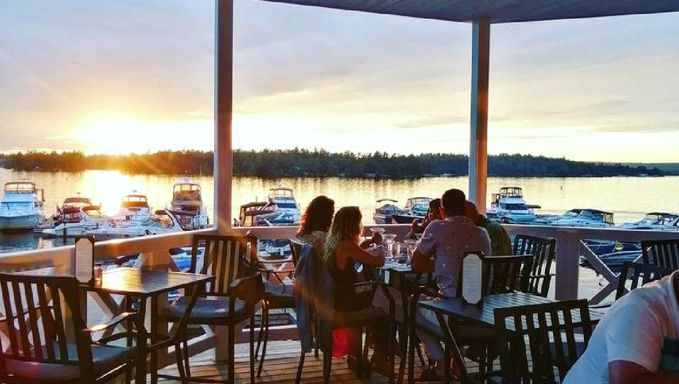 A group of people are sitting at tables overlooking a body of water.