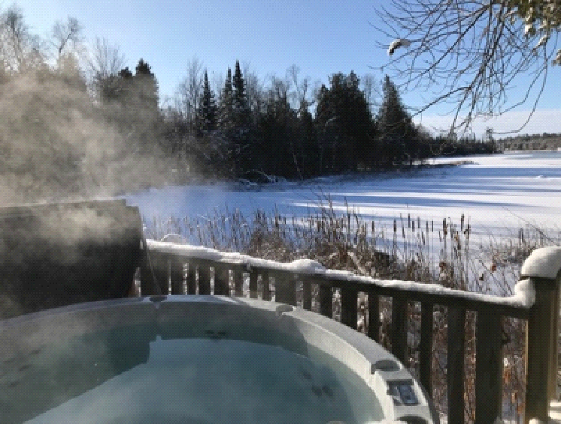 A hot tub on a deck overlooking a snowy field.