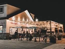 A group of people are sitting outside of a restaurant at night.