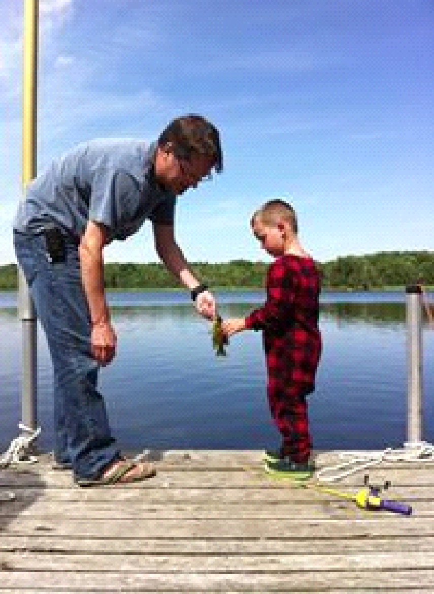 A man and a little boy are fishing on a dock.