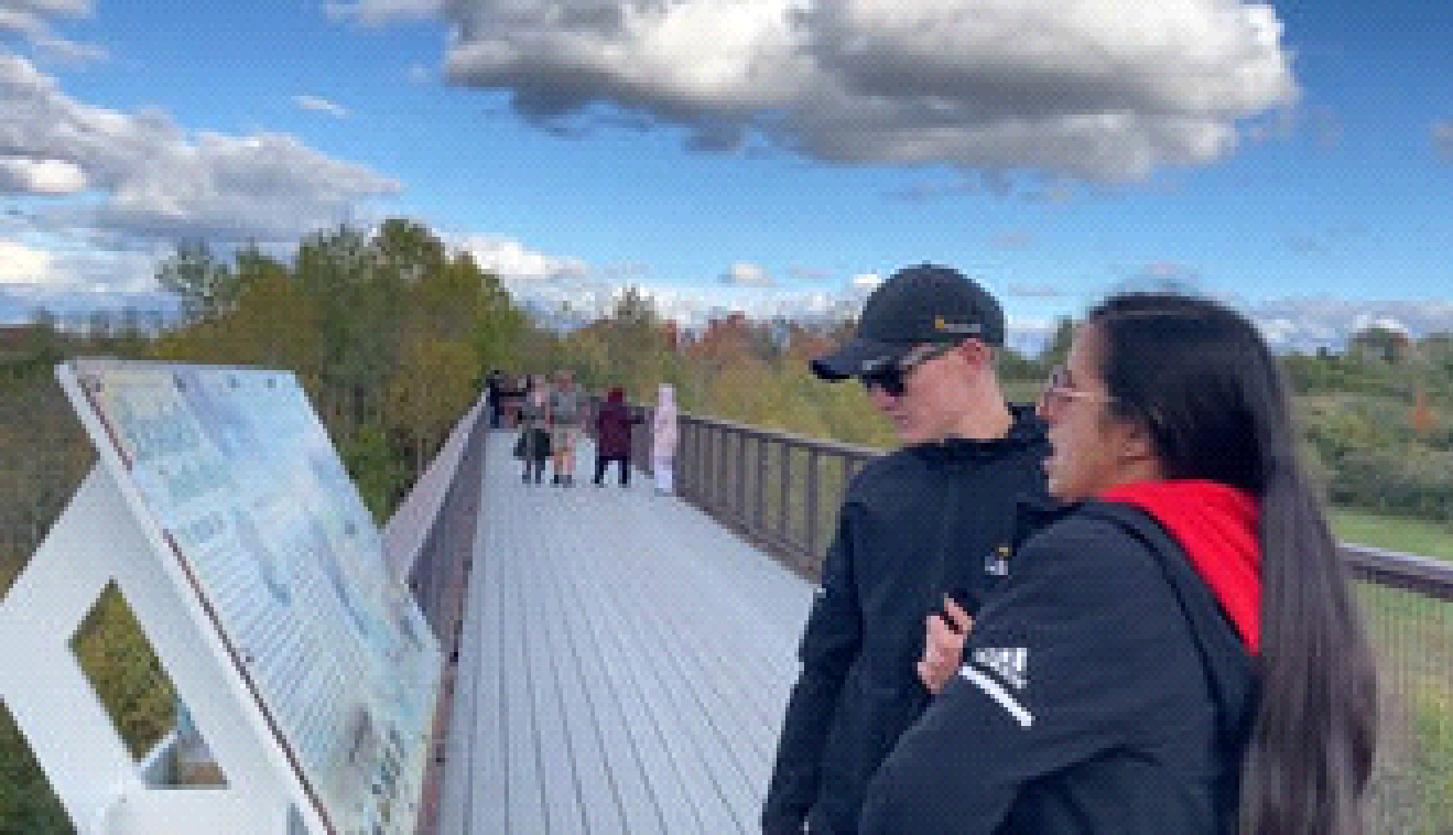 A man and a woman are standing on a bridge looking at a map.